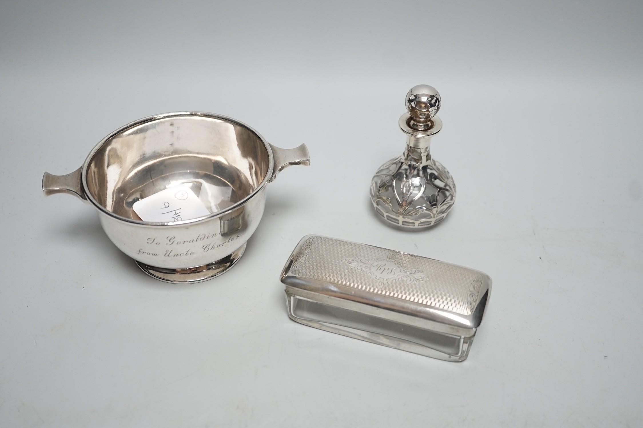 A George V silver two handled bowl, 14.6cm over handles, a white metal overlaid glass scent bottle (a.f.), a silver mounted blotter and a silver mounted glass toilet jar.
